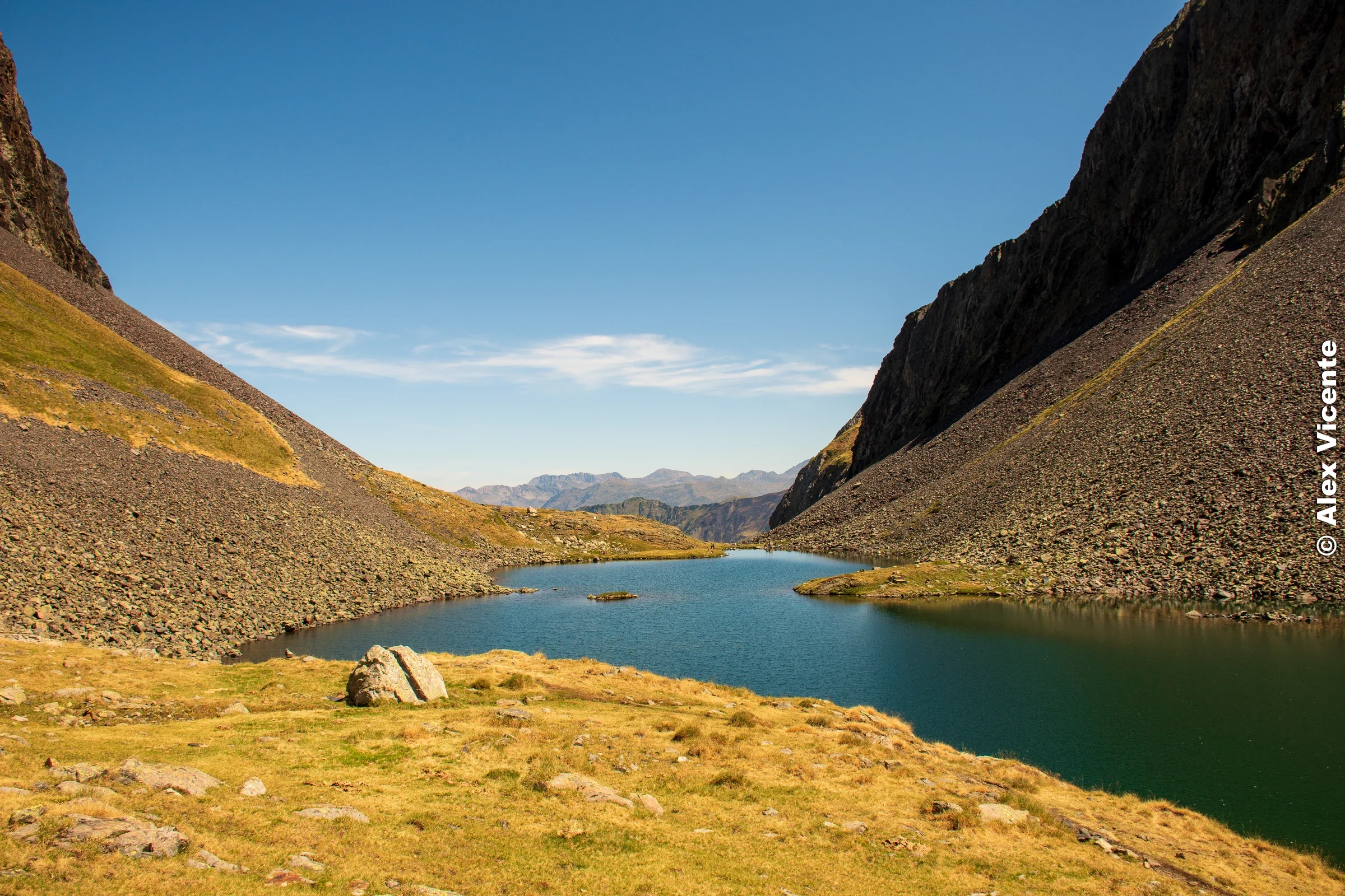 An alpine lake between two steep rocky slopes.